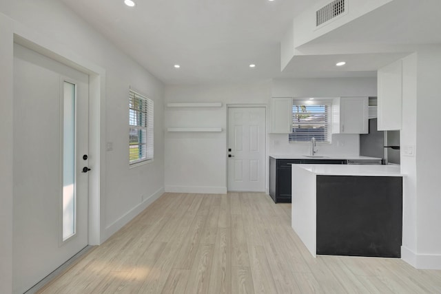 kitchen featuring visible vents, white cabinets, light countertops, freestanding refrigerator, and light wood finished floors