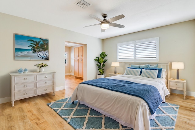 bedroom with light wood-type flooring, baseboards, visible vents, and a ceiling fan