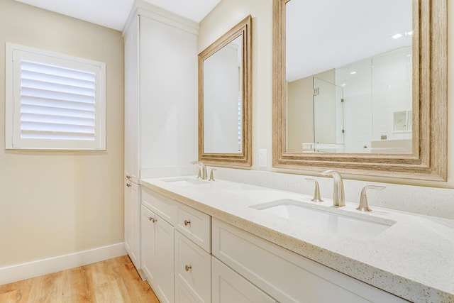 full bathroom featuring double vanity, a sink, baseboards, and wood finished floors