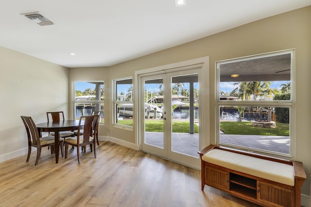 dining space with french doors, light wood-style flooring, visible vents, and baseboards