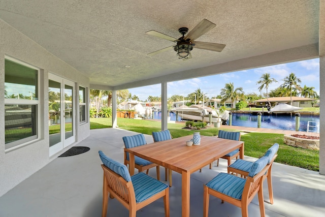 view of patio featuring ceiling fan, outdoor dining area, and a water view