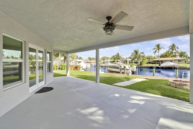 view of patio / terrace with a ceiling fan, a dock, a water view, and a residential view