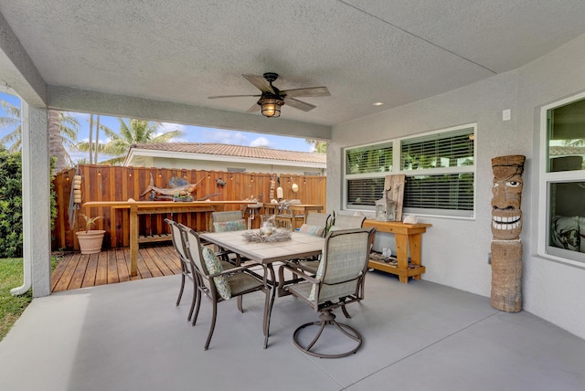 view of patio / terrace featuring ceiling fan, fence, outdoor dining area, and a wooden deck