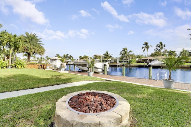 view of yard with a fire pit, a dock, a water view, and boat lift