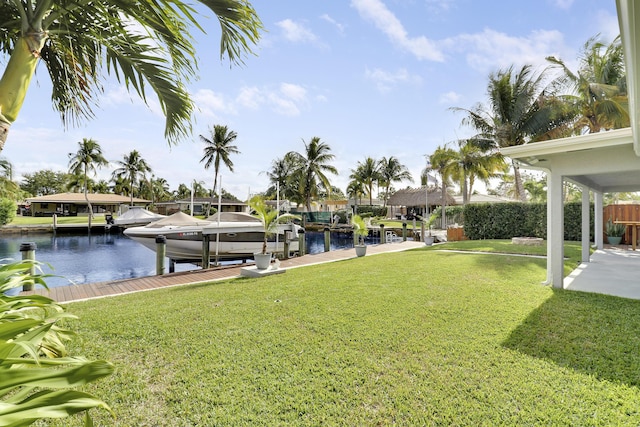 view of dock with a lawn, a water view, boat lift, and fence