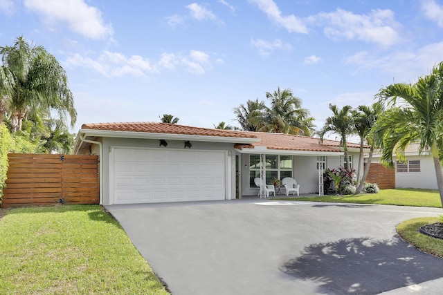 view of front of home with a garage, fence, driveway, a tiled roof, and a front yard