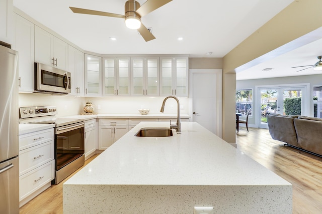 kitchen with ceiling fan, a sink, open floor plan, appliances with stainless steel finishes, and an island with sink