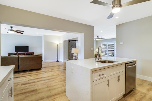 kitchen with light wood finished floors, open floor plan, white cabinets, a sink, and baseboards