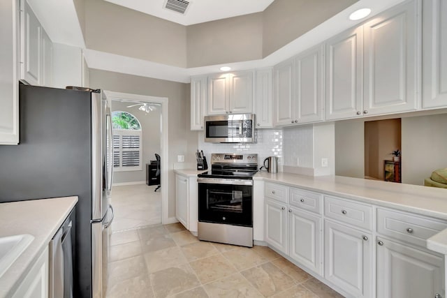 kitchen with stainless steel appliances, light countertops, visible vents, backsplash, and white cabinetry