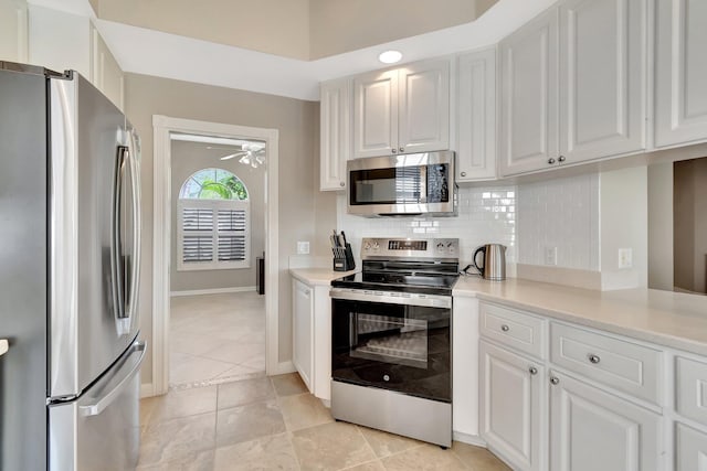 kitchen featuring tasteful backsplash, white cabinetry, stainless steel appliances, and light countertops