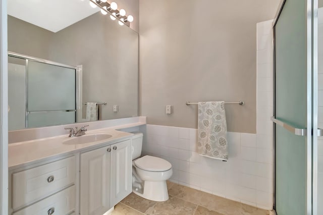 full bath with toilet, a wainscoted wall, an enclosed shower, vanity, and tile walls