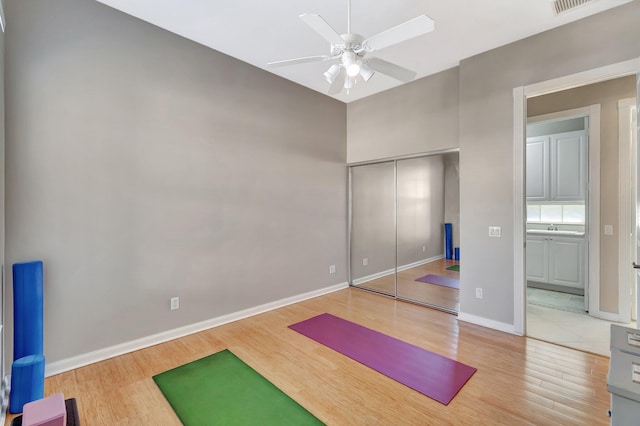 workout room with visible vents, wood finished floors, a ceiling fan, and baseboards