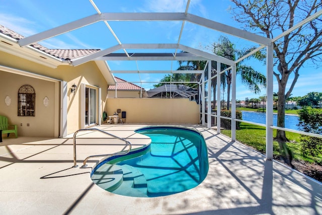 outdoor pool with a water view, a patio area, and glass enclosure