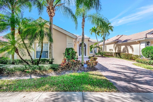 mediterranean / spanish-style home with decorative driveway, a tile roof, and stucco siding