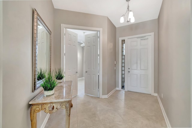 entrance foyer featuring light tile patterned flooring, baseboards, and an inviting chandelier