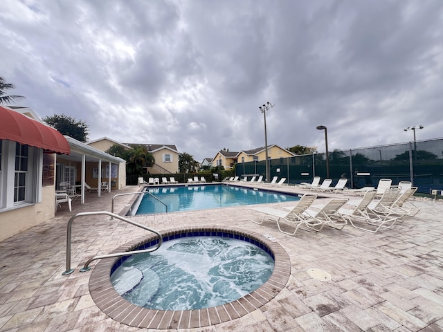 pool featuring a community hot tub, fence, and a patio