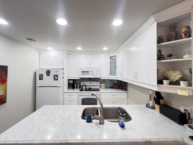 kitchen with white appliances, visible vents, white cabinets, and a sink