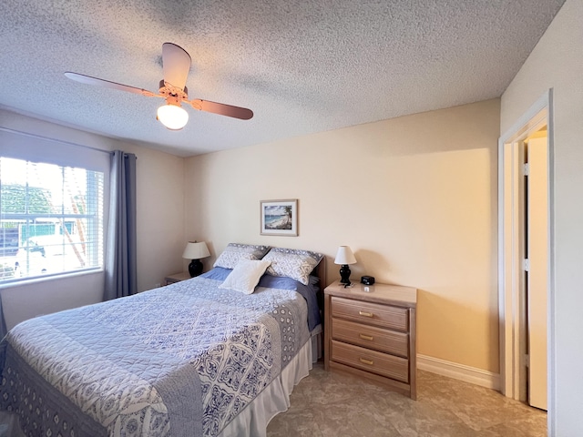 bedroom with ceiling fan, baseboards, and a textured ceiling