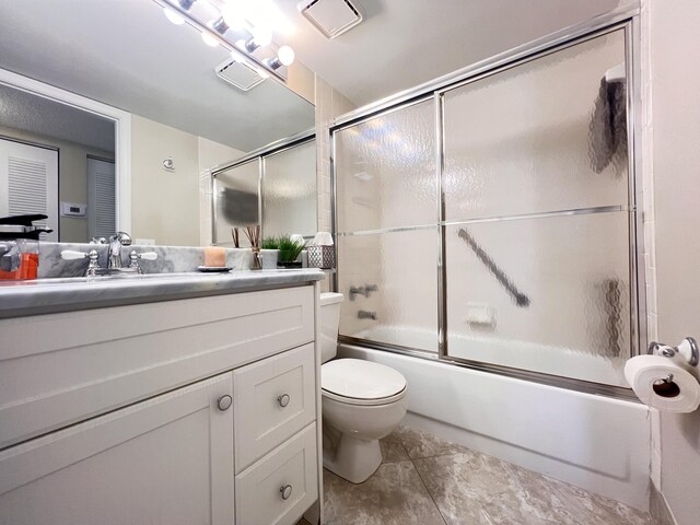 bathroom featuring toilet, bath / shower combo with glass door, visible vents, and vanity