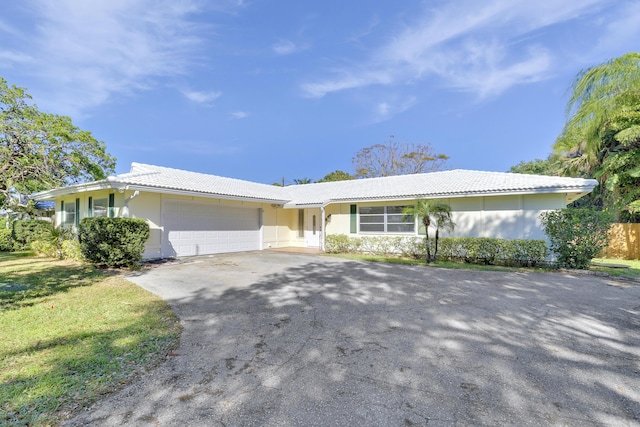 ranch-style house with a garage, a tile roof, aphalt driveway, and stucco siding