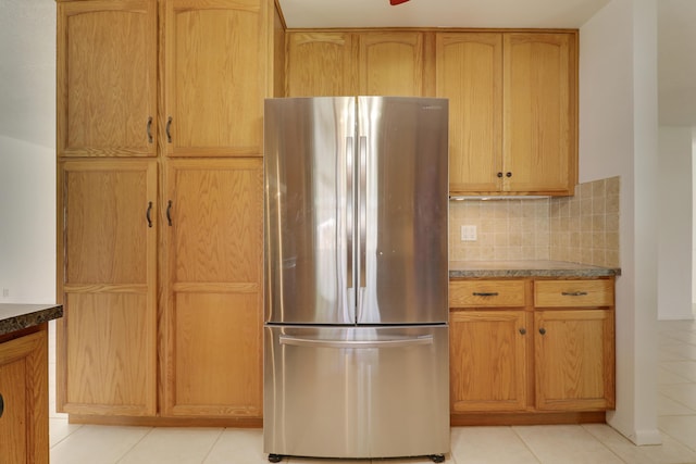 kitchen featuring tasteful backsplash, freestanding refrigerator, and light tile patterned flooring