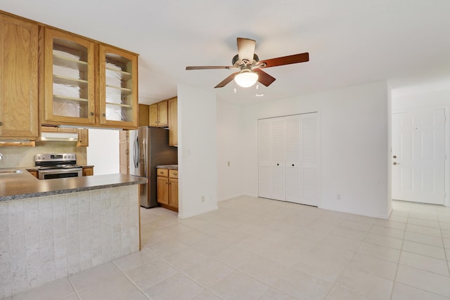 kitchen with decorative backsplash, appliances with stainless steel finishes, glass insert cabinets, a ceiling fan, and under cabinet range hood