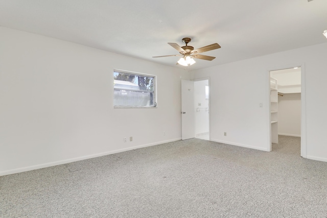 unfurnished bedroom with carpet floors, a ceiling fan, baseboards, a closet, and a walk in closet