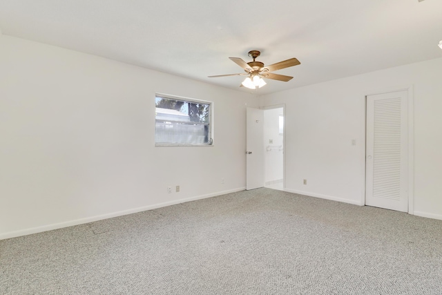 carpeted empty room featuring ceiling fan and baseboards