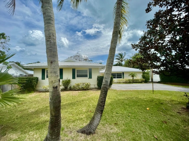 ranch-style house with driveway, a front lawn, and a tile roof