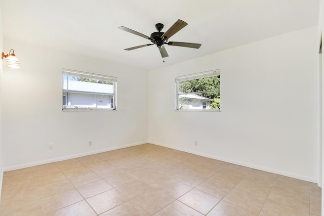 spare room featuring ceiling fan, a wealth of natural light, and baseboards