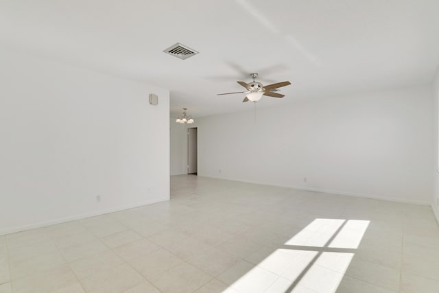 empty room with ceiling fan with notable chandelier, visible vents, and baseboards