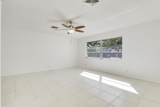 unfurnished room featuring baseboards, light tile patterned flooring, visible vents, and a ceiling fan