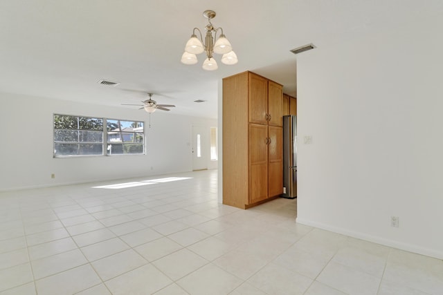 empty room featuring light tile patterned floors, ceiling fan with notable chandelier, and visible vents