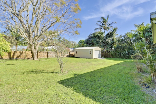 view of yard with an outbuilding, a fenced backyard, and a detached garage