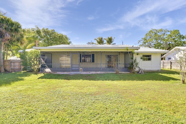 back of property with a sunroom, a lawn, and fence