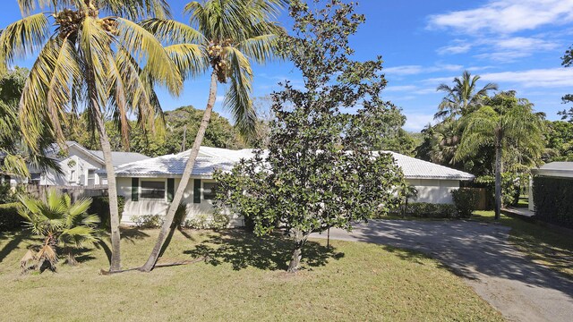 obstructed view of property with a front yard, concrete driveway, a tile roof, and stucco siding