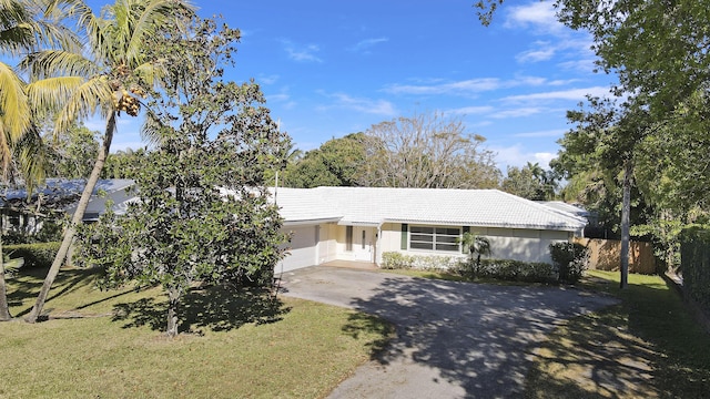 ranch-style house with a garage, concrete driveway, a tile roof, fence, and a front lawn