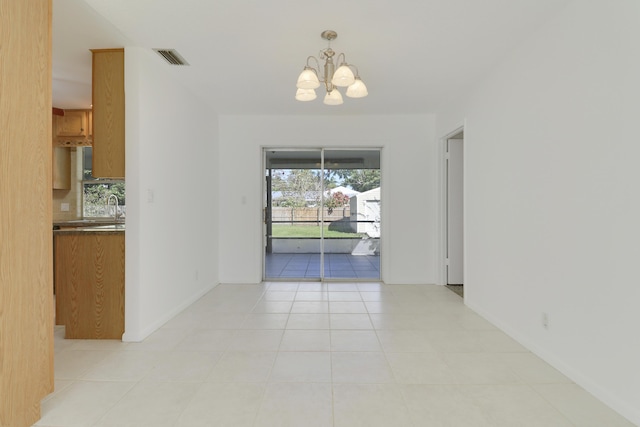 empty room with visible vents, a notable chandelier, a sink, and light tile patterned floors