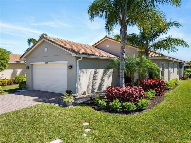 mediterranean / spanish-style home with stucco siding, a tiled roof, an attached garage, decorative driveway, and a front yard