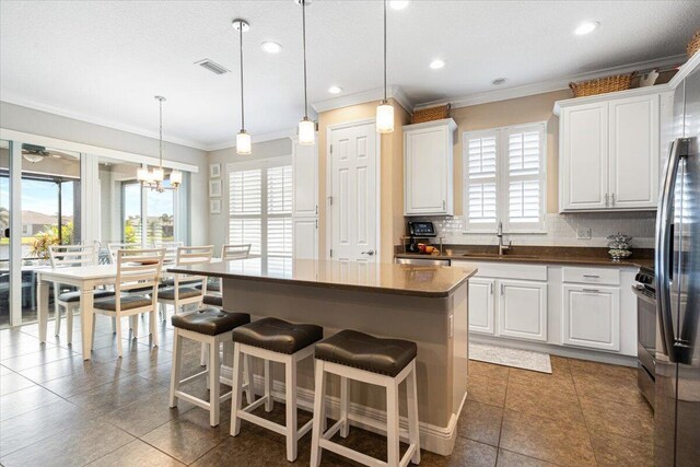 kitchen with visible vents, decorative backsplash, white cabinets, dark countertops, and a sink