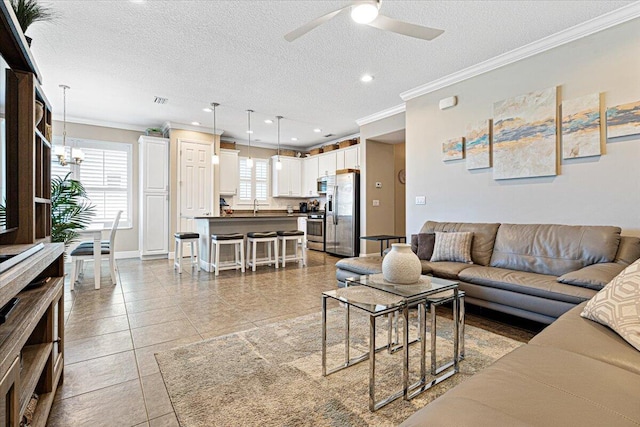 living room featuring light tile patterned floors, ceiling fan with notable chandelier, a textured ceiling, crown molding, and recessed lighting