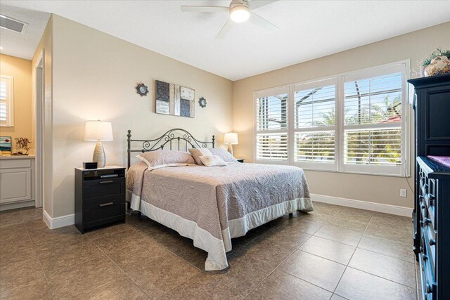 tiled bedroom featuring visible vents, ceiling fan, ensuite bath, and baseboards