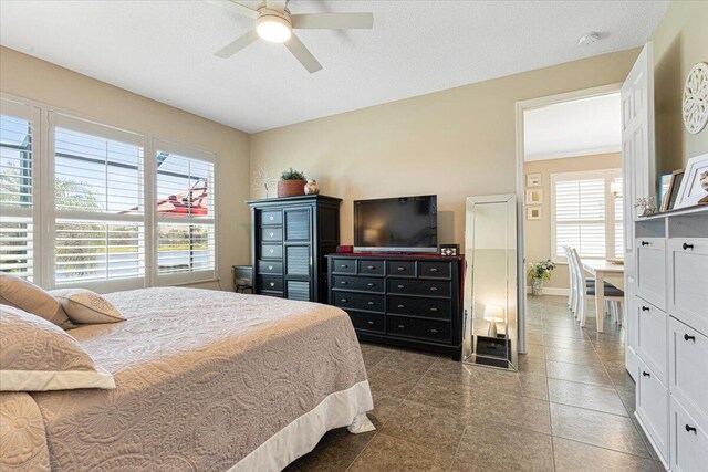 tiled bedroom with ceiling fan, baseboards, and a textured ceiling