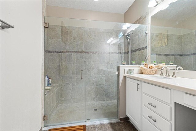 full bathroom with a stall shower, tile patterned flooring, a textured ceiling, and vanity