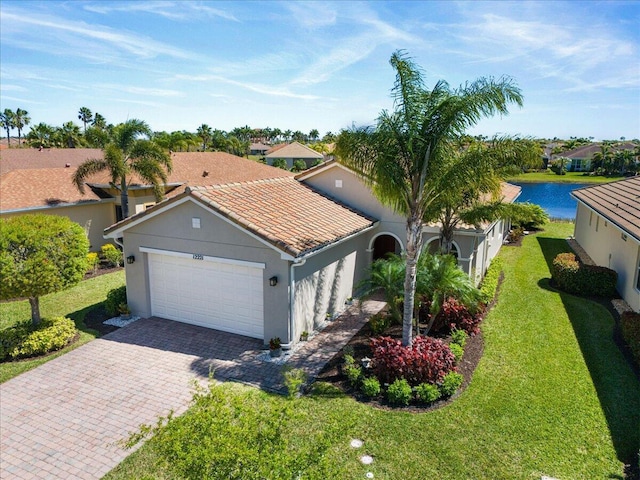 view of front of house with a tiled roof, an attached garage, decorative driveway, a front lawn, and stucco siding