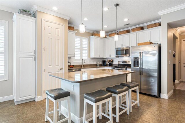 kitchen with a breakfast bar, tasteful backsplash, appliances with stainless steel finishes, ornamental molding, and a sink