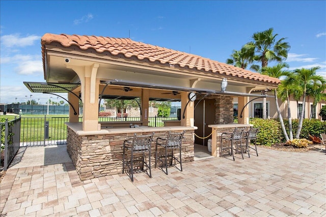 view of patio with a ceiling fan, fence, and outdoor dry bar