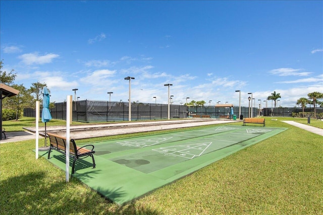 view of home's community with fence, shuffleboard, and a yard