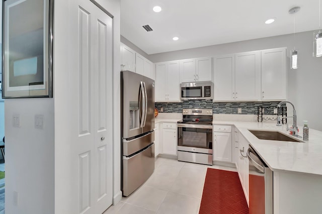 kitchen with light tile patterned flooring, decorative backsplash, appliances with stainless steel finishes, and a sink