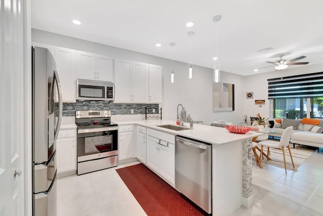 kitchen featuring a sink, stainless steel appliances, light countertops, open floor plan, and tasteful backsplash